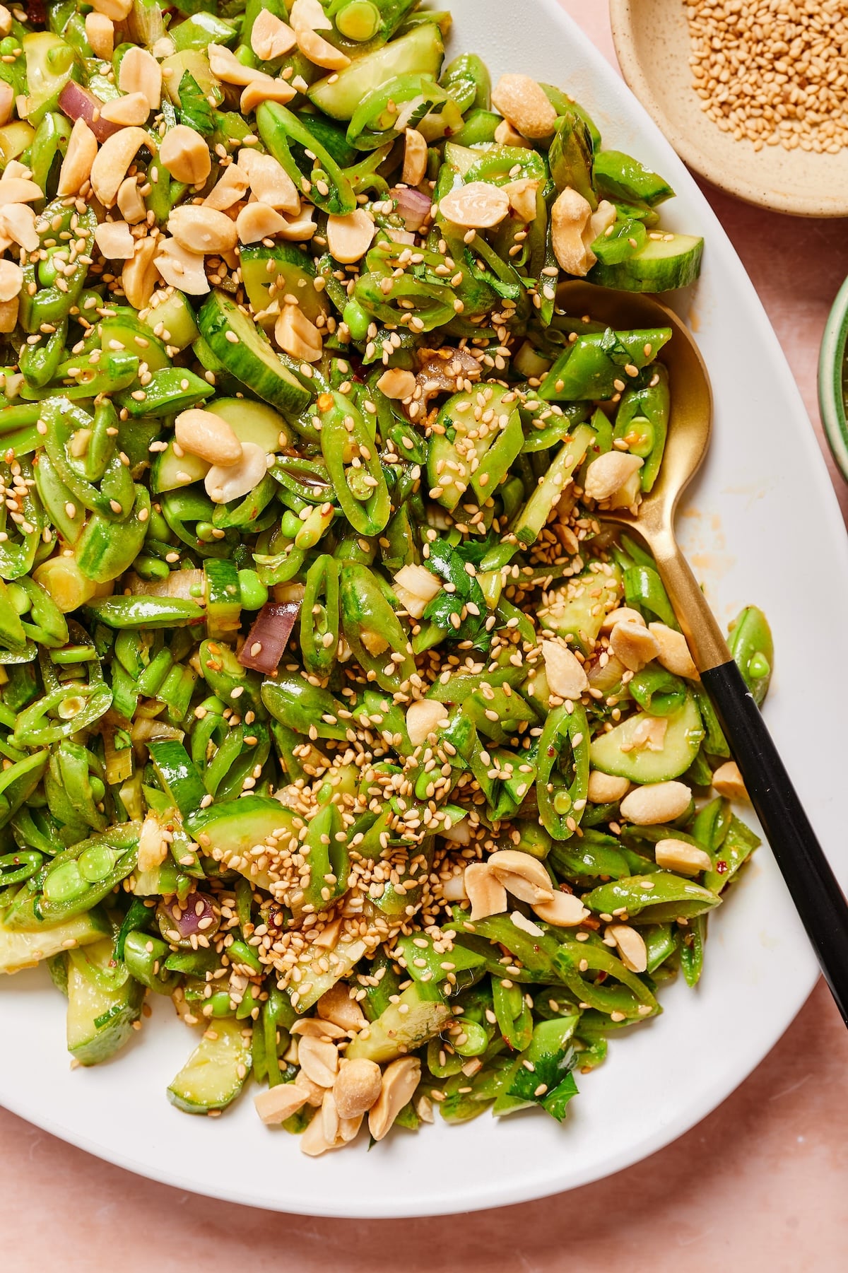 Close-up of sugar snap pea salad with a serving spoon resting in it.