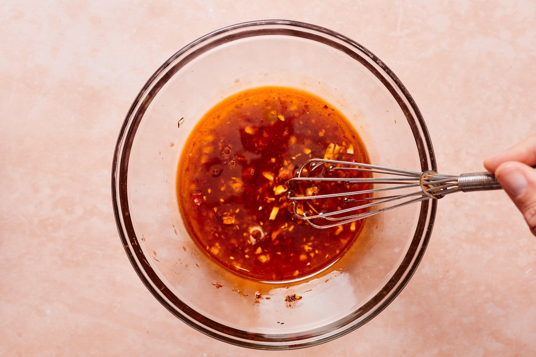Ginger sesame dressing ingredients being whisked together in a small glass bowl.