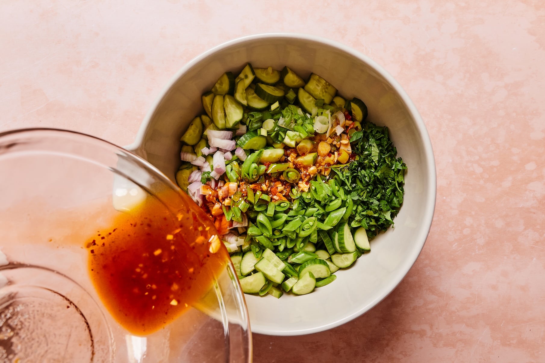 Ginger sesame dressing being poured over the sugar snap pea salad.
