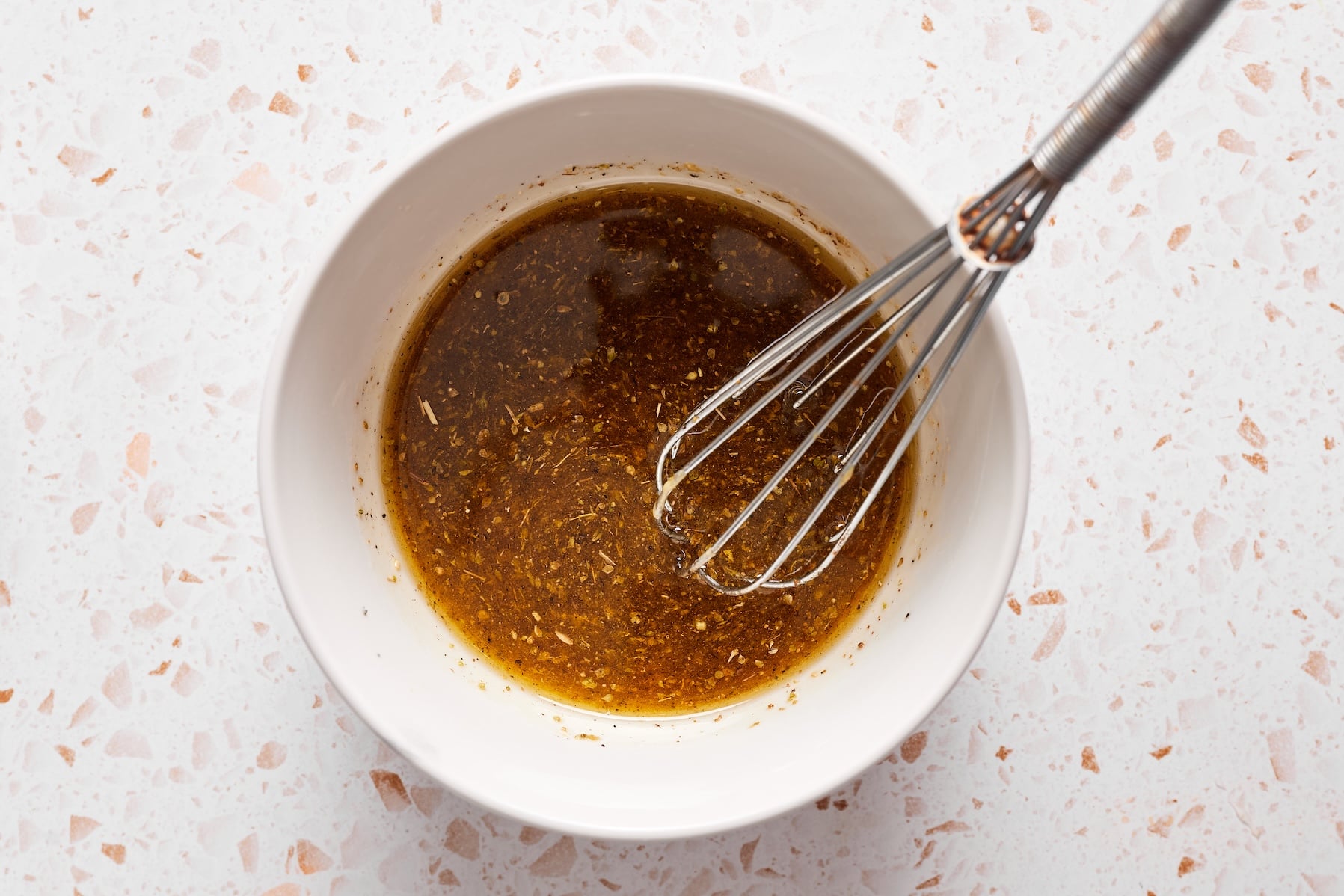 Chickpea pasta salad dressing ingredients whisked together in a mixing bowl.