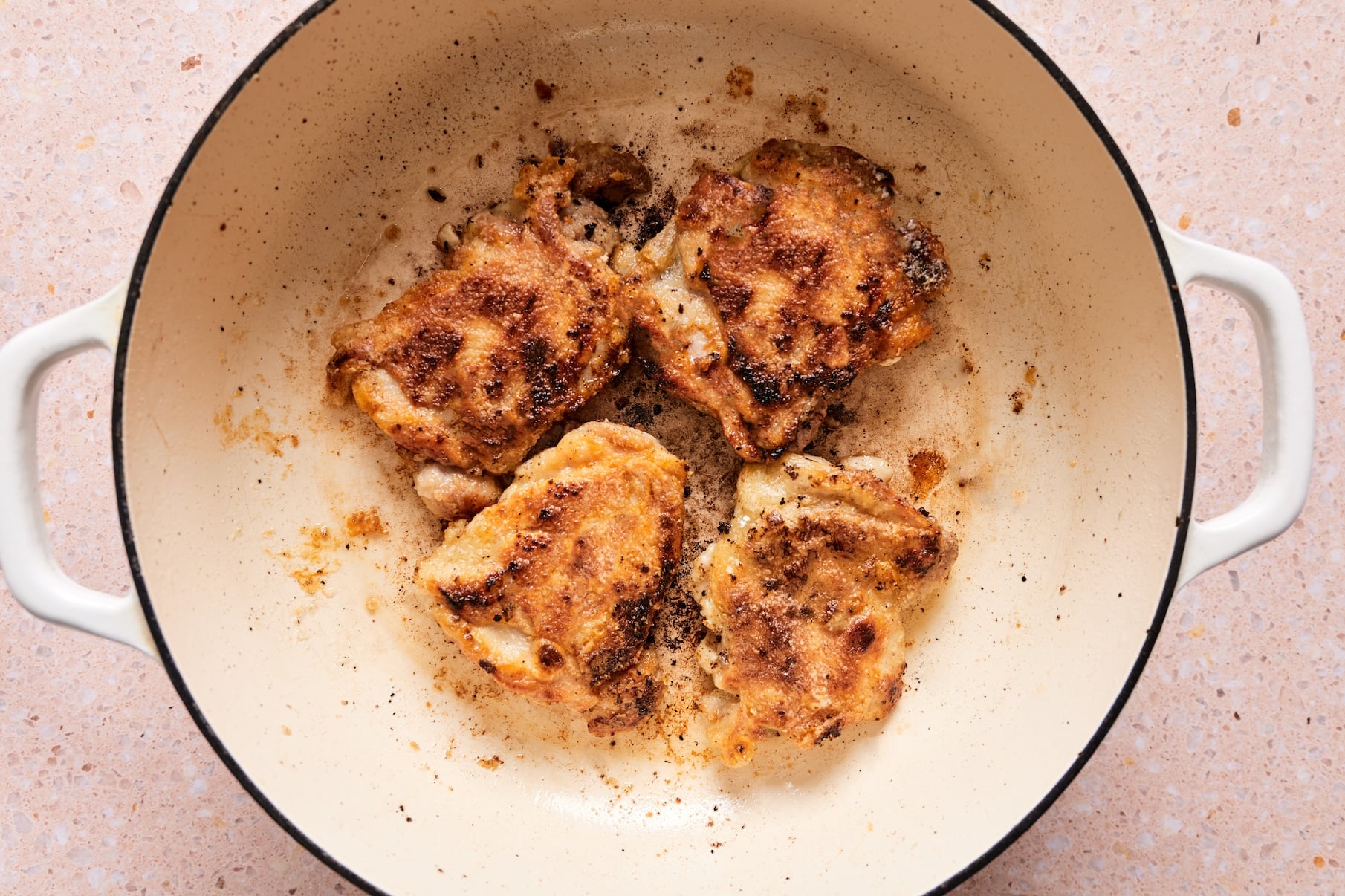 Crispy chicken thighs in a skillet after cooking.