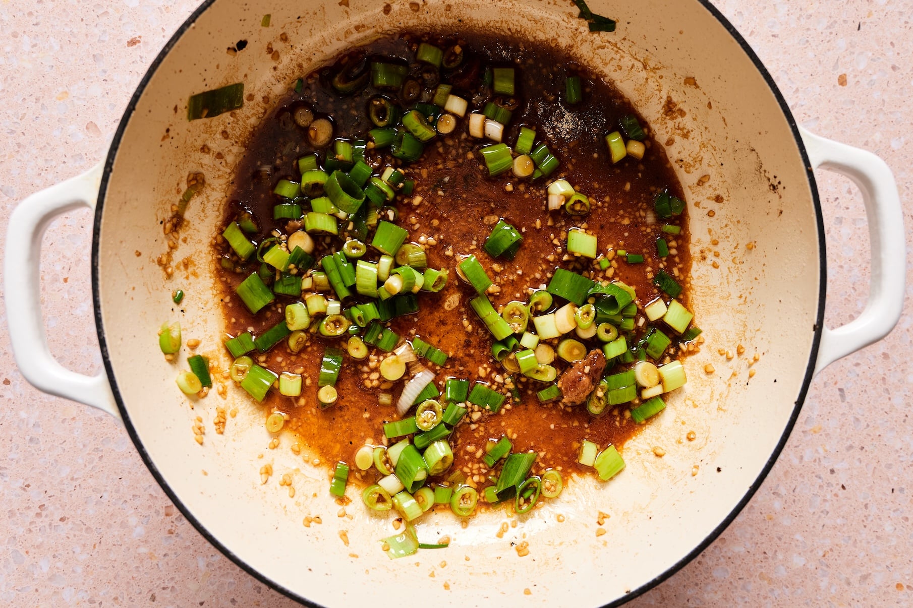 Green onions, tamari, oyster sauce, sesame oil, and sugar added to the skillet with the scallion whites and garlic.