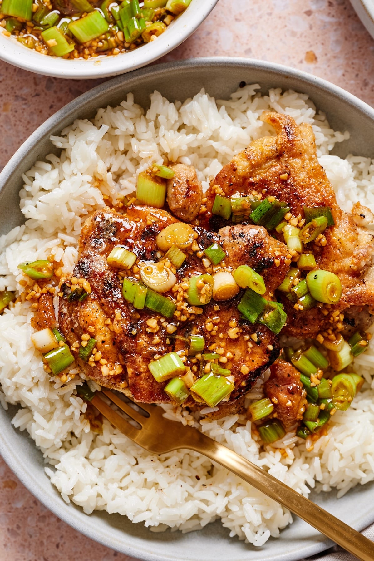 A bowl of crispy scallion chicken with a fork in it.