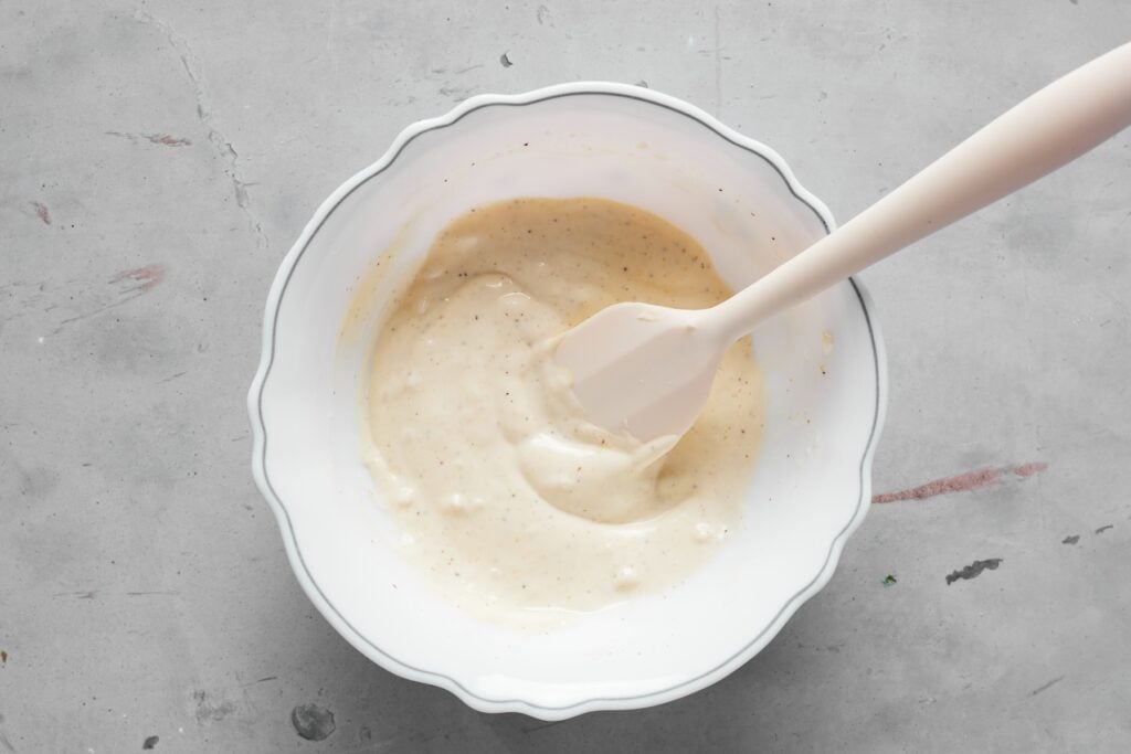 Creamy garlic aioli ingredients mixed together in a small white bowl.
