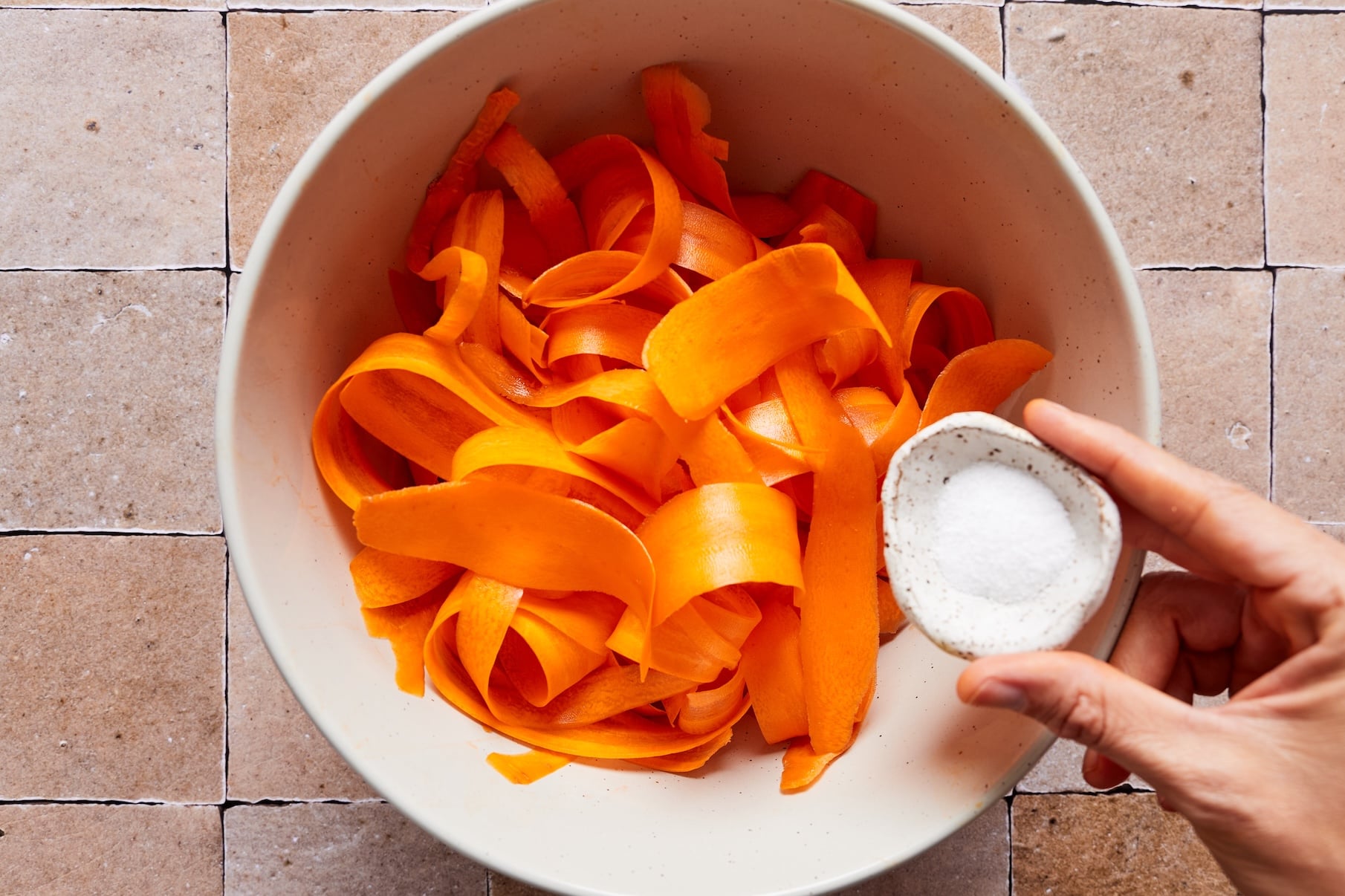 Adding salt to carrot ribbons to let it sit and wilt