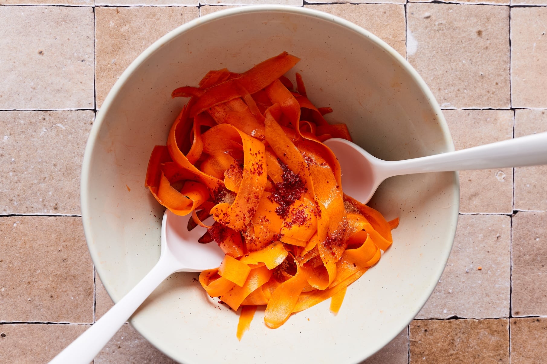 Tossing carrot ribbons with rice vinegar, sugar, and gochugaru