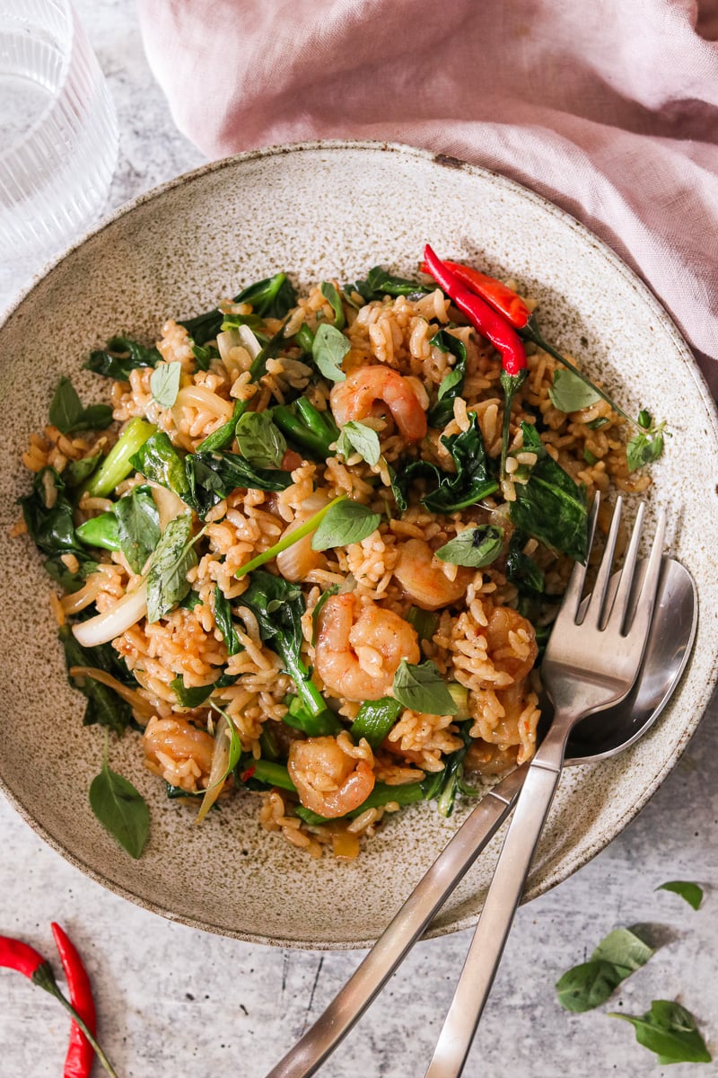 a bowl of drunken fried rice garnished with fresh Thai basil.