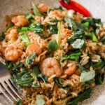 an up close shot of drunken fried rice topped with cooked shrimp and fresh Thai basil.