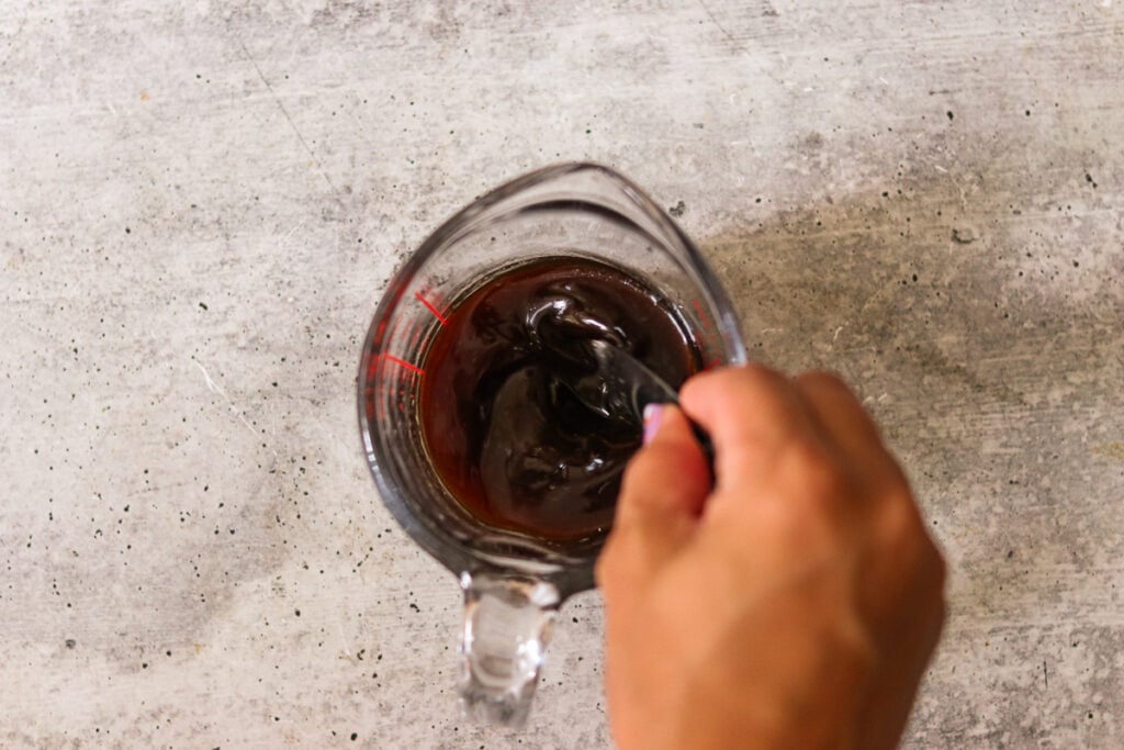 a hand mixing a jar of sauce