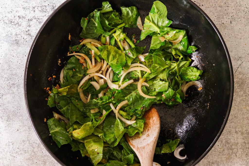 adding the greens and onions in a wok to sautee