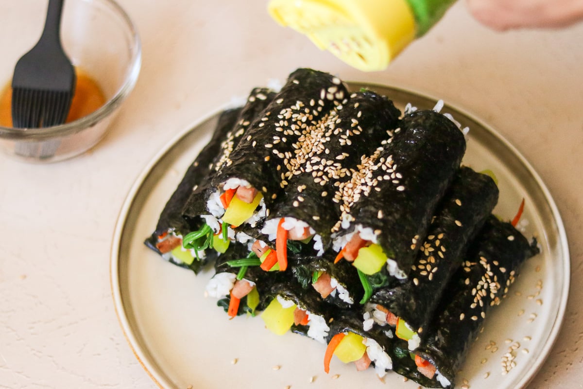 Rolled mini kimbap brushed with sesame oil and sprinkled with sesame seeds before serving.