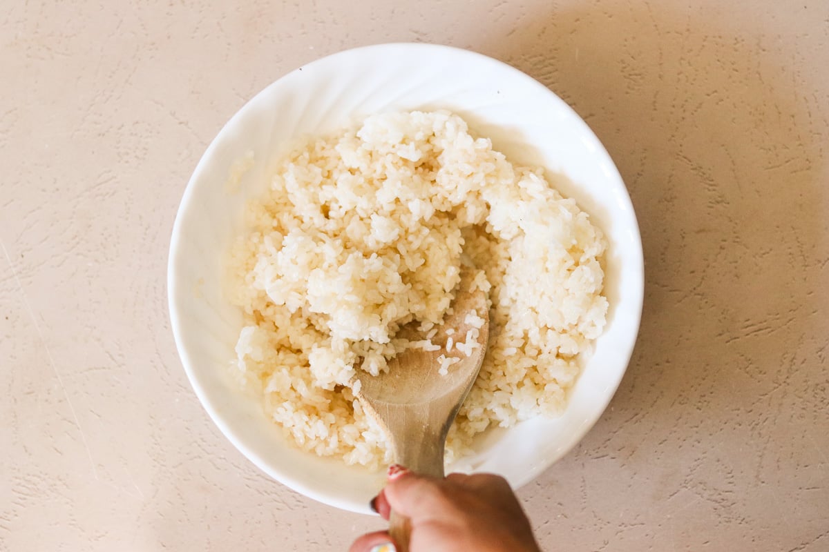 Cooked rice gently tossed with sesame oil and sea salt in a small white bowl.