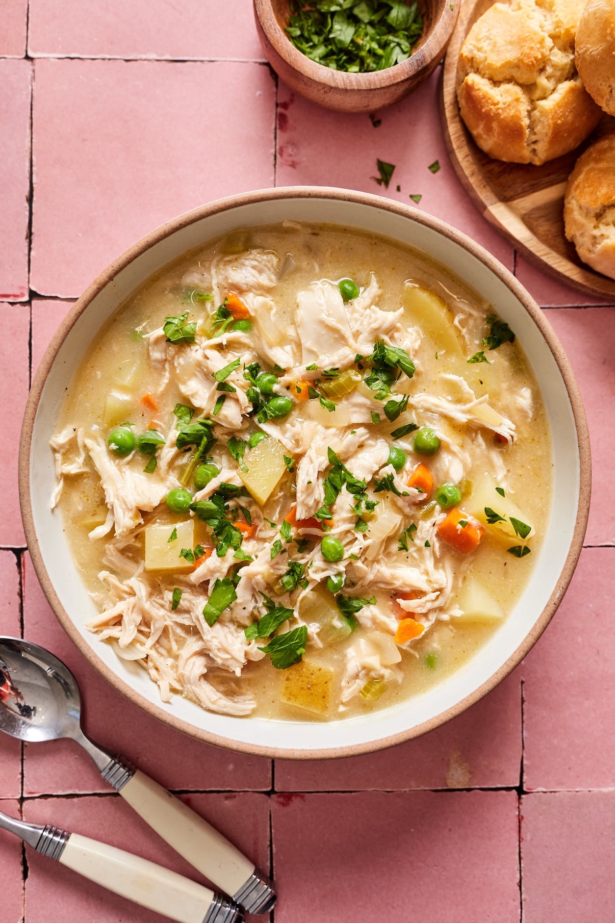 A bowl of chicken pot pie soup in a bowl showing the peas, chicken, carrots, and potatoes.