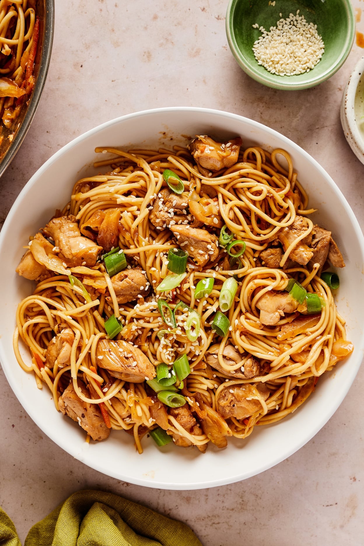 Honey garlic chicken noodles garnished with green onions and sesame seeds in a small bowl; ready to eat.