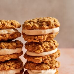 Two stacks of gluten free pumpkin oatmeal cream pies with a creamy brown butter filling in the middle.