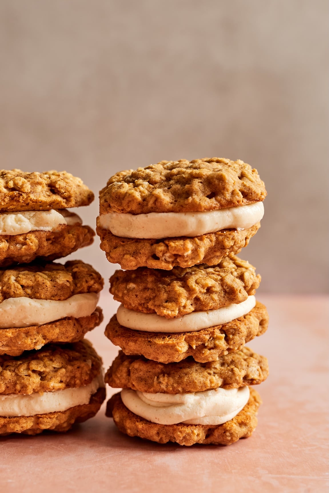 Two stacks of gluten free pumpkin oatmeal cream pies with a creamy brown butter filling in the middle.
