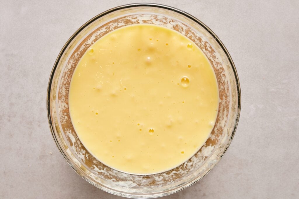 Whisked eggs and yogurt in a glass bowl.