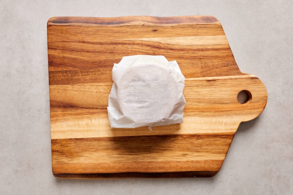 A breakfast sandwich wrapped in parchment paper ready to go into the freezer.