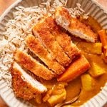 chicken katsu with a homemade Japanese curry served over short grain rice in a bowl.