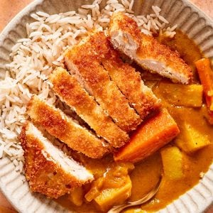 chicken katsu with a homemade Japanese curry served over short grain rice in a bowl.