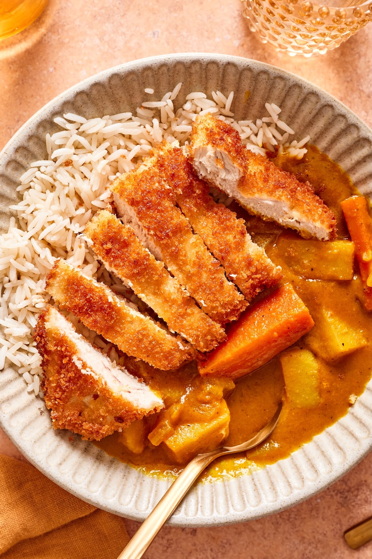 A close up of chicken katsu with a homemade Japanese curry served over short grain rice in a bowl.