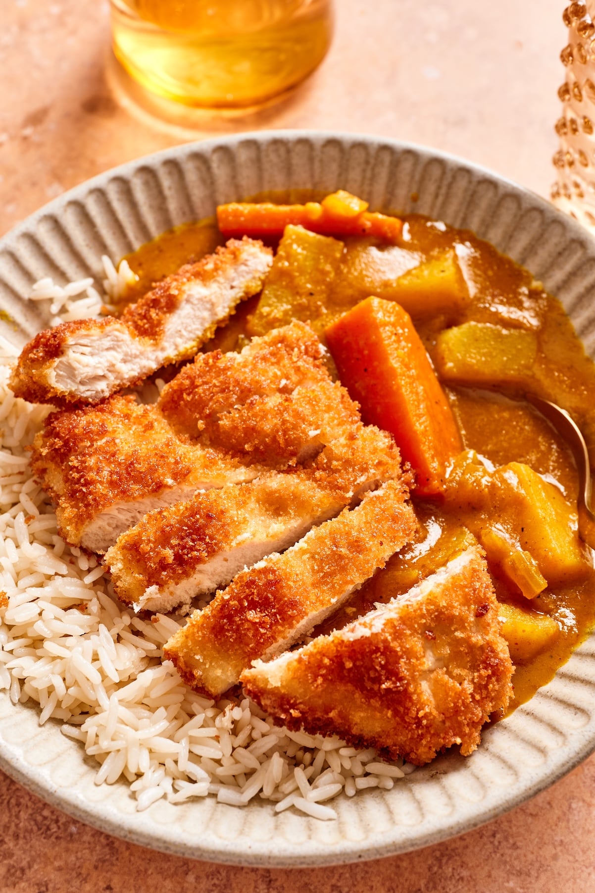 a close up of a sliced, fried chicken cutlet on top of the japanese curry.