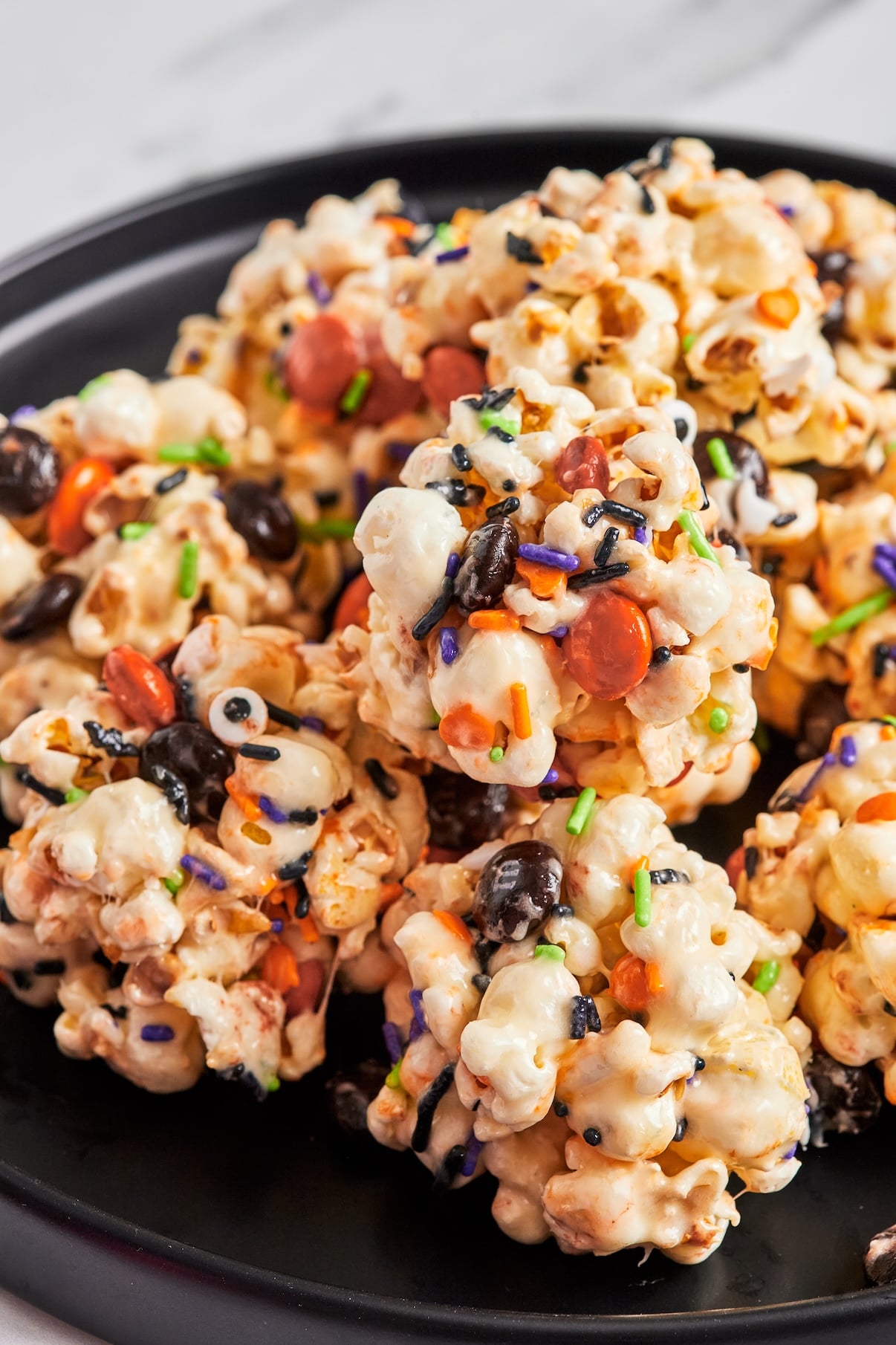 Popcorn balls rolled in Halloween sprinkles with candy eyeballs pressed on top