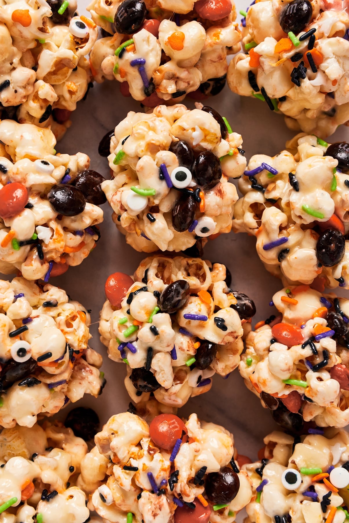 Halloween marshmallow popcorn balls with black and orange M&Ms, candy eyeballs, and Halloween sprinkles