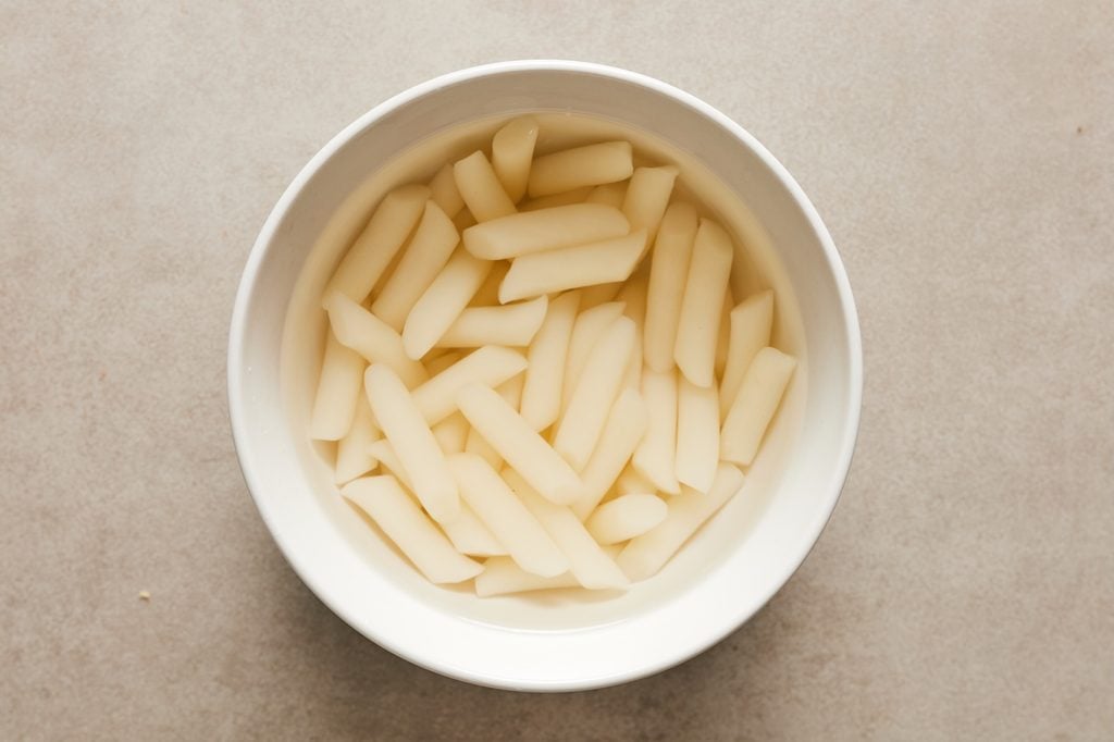Rice cakes soaking in a white bowl of warm water.