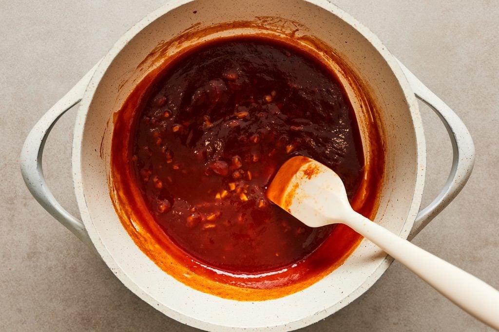 Simmering sweet and spice sauce ingredients in a saucepan before tossing with the Korean popcorn chicken.